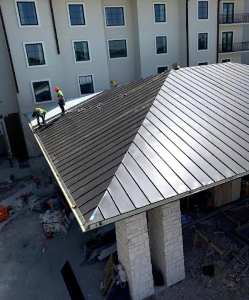 Crew installing standing seam metal roof panels on a commercial project in Montville